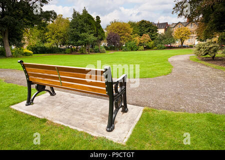 Park bench in a small urban park with landscaped gardens England, UK Stock Photo