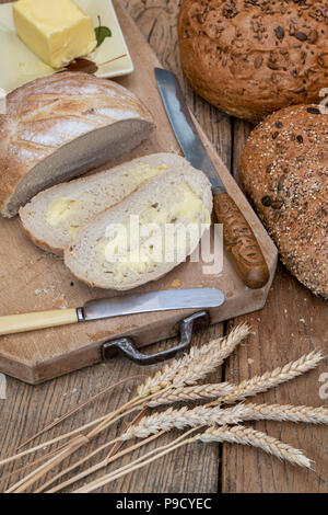 Sliced White bread with seeded loaves on a bread board with wheat and a bread knife. UK Stock Photo