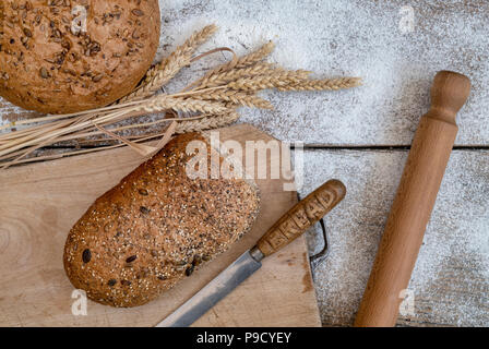 Seeded bread on a bread board with wheat and a bread knife. UK Stock Photo