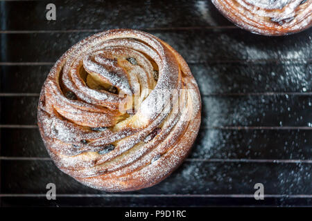 Cupcake pie crunch in the form of a roll sprinkled with powdered sugar on a dark background and an antique grille. Easter and Christmas baking. Top vi Stock Photo