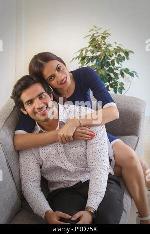 Portrait of a young woman leaning over a young man from behind Stock Photo