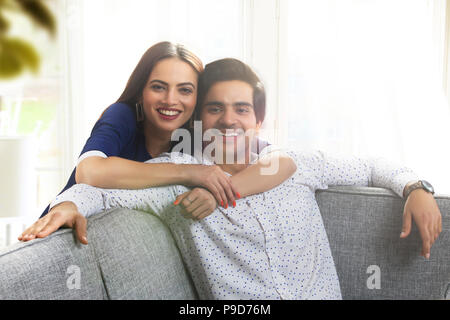 Portrait of a young woman leaning over a young man from behind Stock Photo
