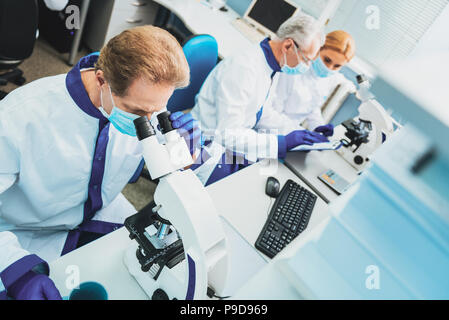 Concentrated researcher using microscope while working Stock Photo
