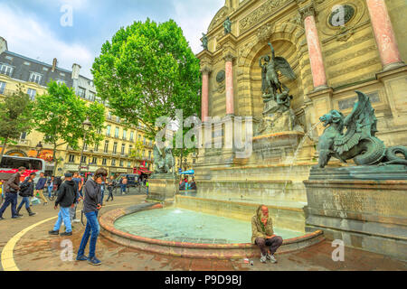 Paris, France - July 1, 2017: clochard and tourists in Place Saint-Michel and monumental Fontaine Saint-Michel with two water-spouting dragons. Historic urban landmark in Paris capital. Stock Photo
