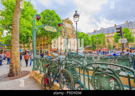 Paris, France - July 1, 2017: Entrance to subway with Fontaine Saint-Michel on background. The sign of the underground in Paris in classical liberty style in Place Saint-Michel. Stock Photo