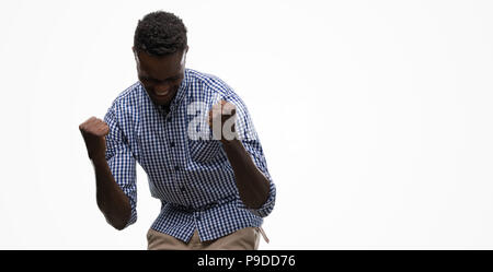 Young african american man wearing blue shirt very happy and excited doing winner gesture with arms raised, smiling and screaming for success. Celebra Stock Photo