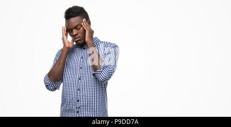 Young african american man wearing blue shirt with hand on head for pain in head because stress. Suffering migraine. Stock Photo