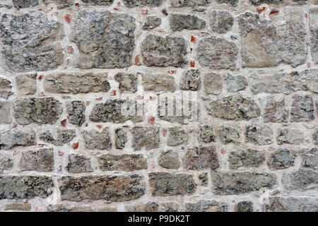 The texture of the restored wall with fragments of red stones Stock Photo
