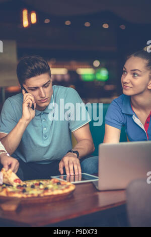 high angle view of young people eating pizza while working together Stock Photo