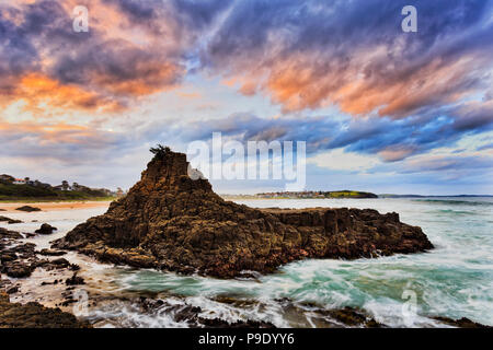 Colourful sunset in clouds and waters around sandstone cliffs off Bombo beach in Kiama of Australia - Pacific coast. Stock Photo