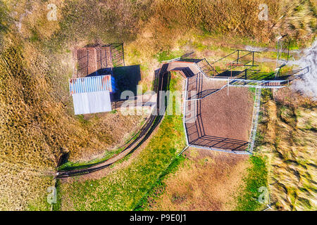The entrance and loading gate at remote country cattle farm on a plain with pasture and grass in aerial top down view on a shed with gate and fence. Stock Photo