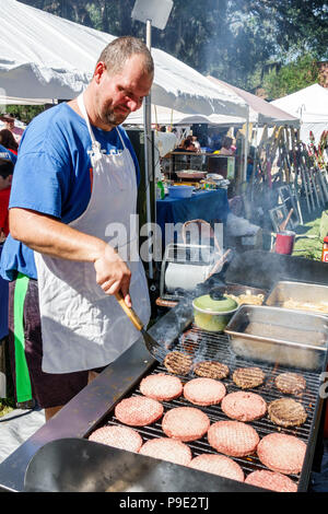 Florida,Micanopy,Fall Harvest Festival,annual small town community booths stalls vendors buying selling,street food,hamburgers,grill,man men male,cook Stock Photo