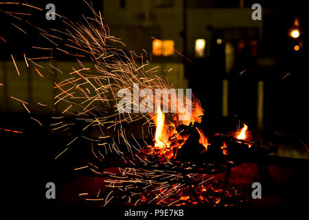 Fire place on a summer night showing the details of the sparks and the flames glowing in the darkness of the night Stock Photo