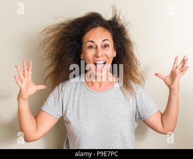 Curled hair brazilian woman very happy and excited, winner expression celebrating victory screaming with big smile and raised hands Stock Photo