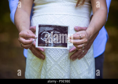 Close up of pregnant belly couple  holding hands and baby scan Stock Photo