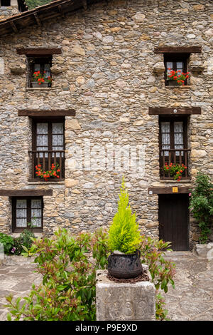 Granite stone house facade with geraniums growing in window boxes in the Pyreneean village of Beget, Catalonia, Spain Stock Photo