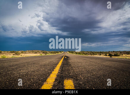 Dark skies over a long straight road Stock Photo