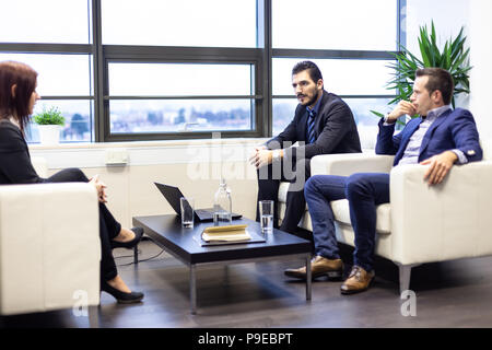 Businessmen interviewing female candidate for job in modern corporate office. Stock Photo
