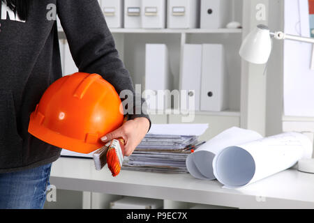 Young architect wearing suit holding helmet, standing in office Stock Photo
