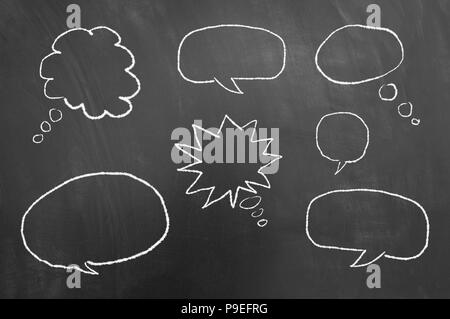 Multiple speech thought bubbles drawing on chalkboard or blackboard as communication balloon thought expression cloud concept Stock Photo