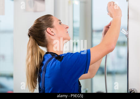 Skilled female worker checking a showerhead in a modern sanitary ware shop Stock Photo
