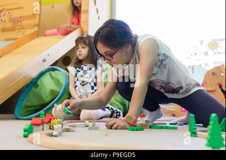 Girl playing with a wooden train circuit in the kindergarten Stock Photo