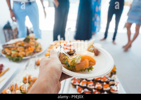 Man helping himself on Buffet of party outdoors taking food  Stock Photo