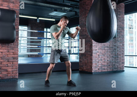 Dark-haired boxer feeling anger while training after losing competition Stock Photo