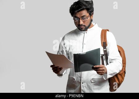 cute indian student is looking at paper isolated on the white background. copy space Stock Photo