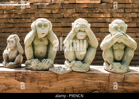 Three wise monkeys and a fourth monkey scratching his head in Wat Umong, Chiang Mai, Thailand Stock Photo