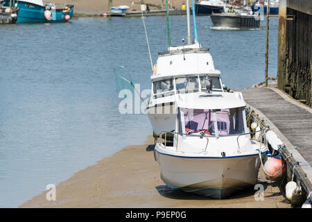 Small pleasure boats moored up on a river at low tide, resting on sand banks on the River Arun in Littlehampton, West Sussex, England, UK. Stock Photo