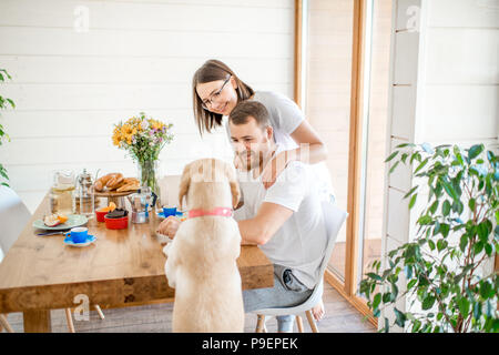 Couple having a breakfast with dog at home Stock Photo