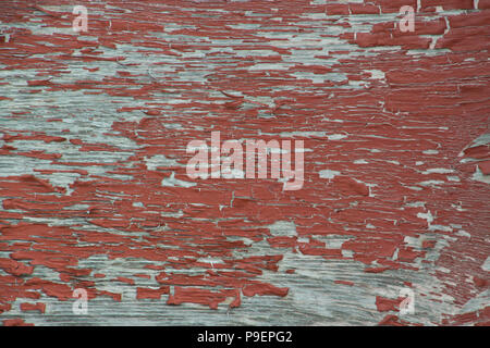 Weathered grungy peeling red paint on old grey plywood background wallpaper Stock Photo