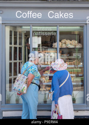 Two mature women shoppers looking in the window of Steins Patisserie and bakers shop in Padstow Cornwall UK Stock Photo