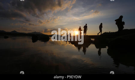 12 July 2018, Germany, Fuessen: Holidaymakers enjoy the sunset on a pier at Hopfensee lake. Photo: Karl-Josef Hildenbrand/dpa Stock Photo