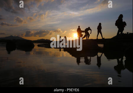 12 July 2018, Germany, Fuessen: Holidaymakers enjoy the sunset on a pier at Hopfensee lake. Photo: Karl-Josef Hildenbrand/dpa Stock Photo