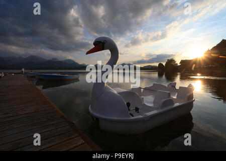 12 July 2018, Germany, Fuessen: A pedal boat in the shape of a swan is at the waterfront of the Hopfensee lake during sunset. Photo: Karl-Josef Hildenbrand/dpa Stock Photo