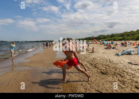 Lifeguards running into the water during rescue action are seen in Gdansk, northern Poland on 6 July 2018 . Their 8 hour working day is divided into 2 Stock Photo