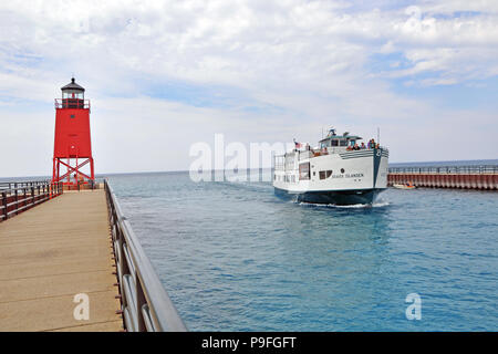 Beaver Islander ferry passes the Charlevoix South Pier Lighthouse on the Island Lake Outlet going from Lake Michigan to Charlevoix Lake (Michigan). Stock Photo