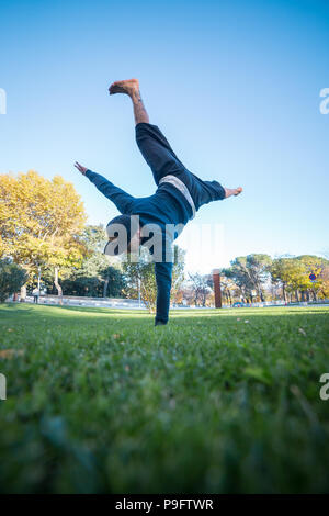 Young man doing handstand on grass in the street while doing parkour. Stock Photo