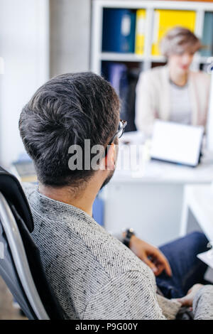 closeup portrait of boss keeping watch over his nice colleague at workplace. see after employee.leader oversees work. blurred background Stock Photo