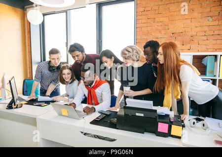 close up portrait of diverse students bending over african man in glasses with laptop. working together Stock Photo