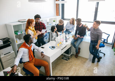 close up top view shot of casually dressed executives duscussing the future project in the studio with panorama window Stock Photo