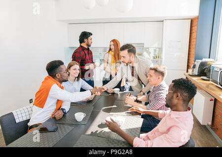 Close-up photo of two business men shaking hands during coffee break in the modern canteen Stock Photo