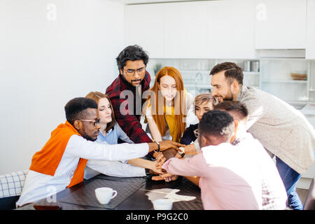 close up image of diverse managers holding hands together in the office kitchen Stock Photo