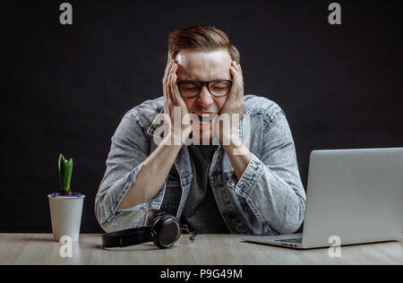 weary and yawning young red haired web-designer at workplace. tiredness concept.sleepy businessman Stock Photo