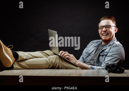laughing young office worker resing on the chair with notebook at work Stock Photo