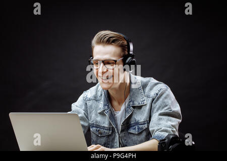 smiling guy listening to music while playing games in the notebook. side view shot Stock Photo