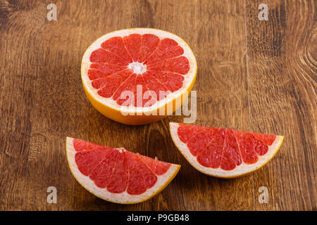 three pieces of sliced fresh juicy ripe grapefruit on wooden backround Stock Photo