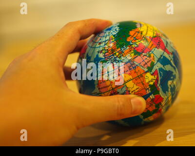 Close Up Hand holding a Mini Globe with Wooden Table Background Stock Photo